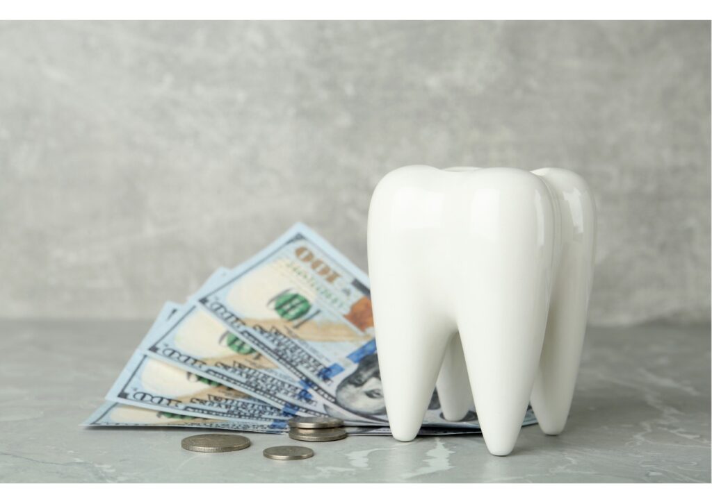 Tooth model beside cash and coins representing the cost of dental implants and tooth replacement treatment