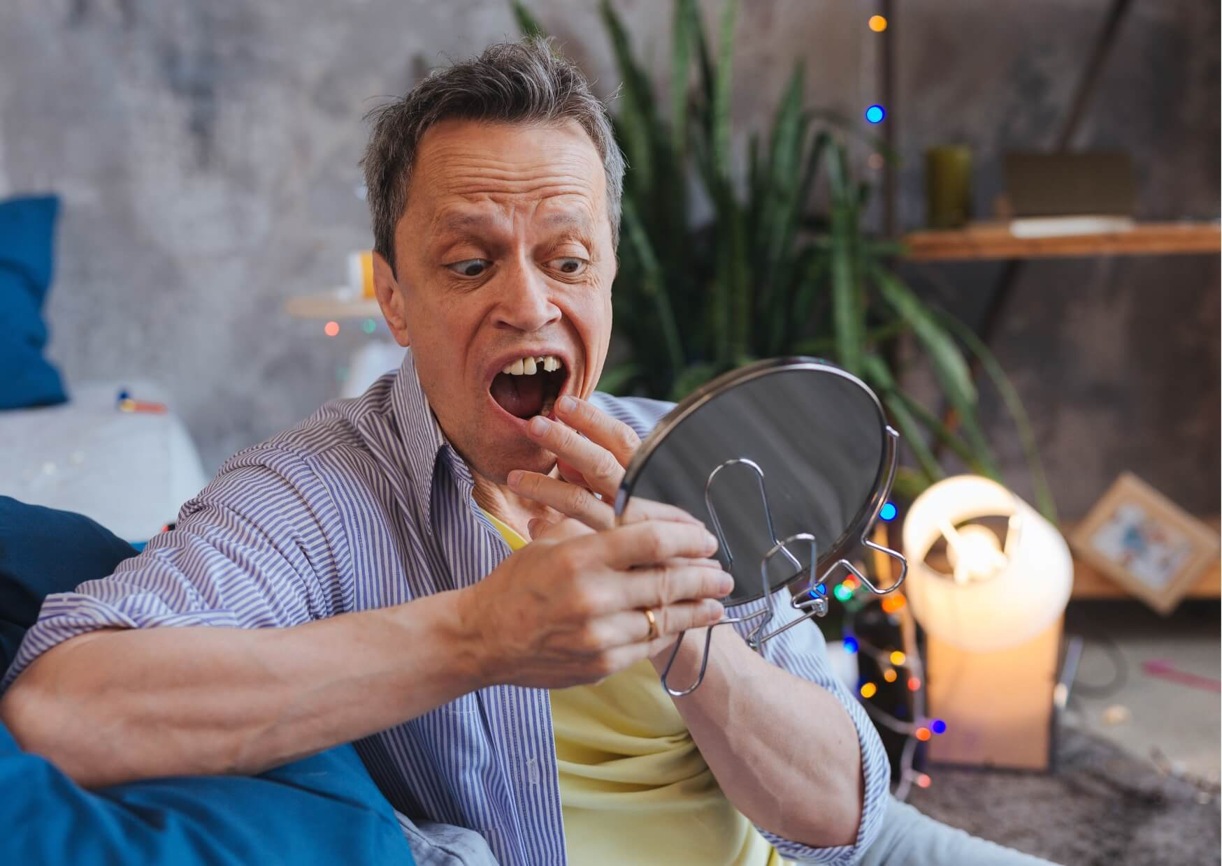 Concerned man checking a loose adult tooth in a mirror, illustrating a common sign that may require prompt dental attention.