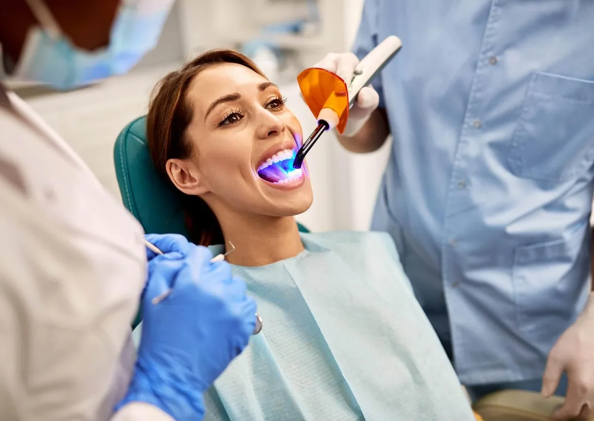 Patient receiving dental bonding treatment with a curing light to improve the appearance of her teeth.