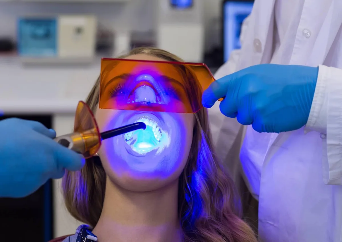Dental sealant treatment being applied to a patient&rsquo;s teeth using a curing light.