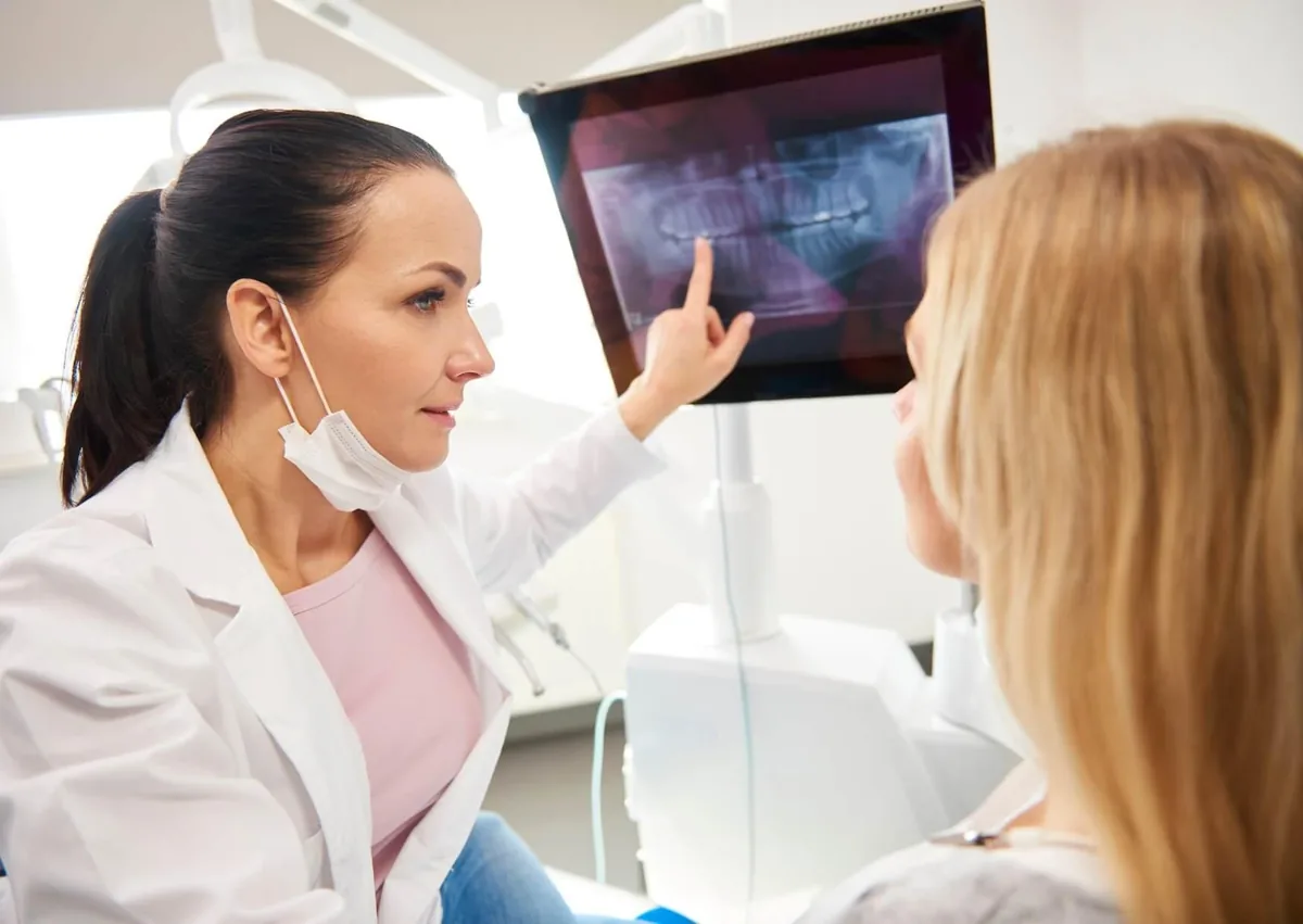 Dentist reviewing dental X-rays with a patient while discussing full mouth dental implants cost and treatment planning.
