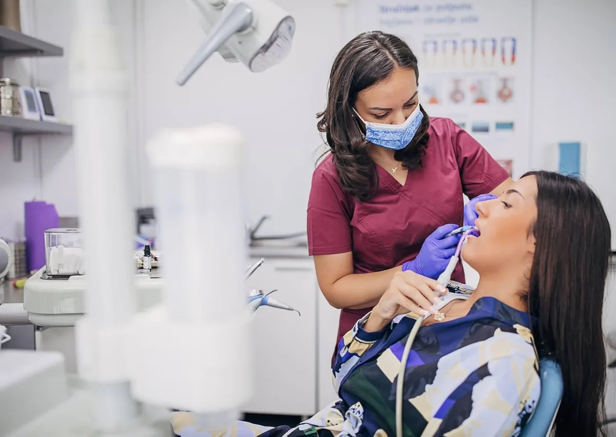 Dental professional cleaning a patient’s teeth to remove plaque and maintain oral health.